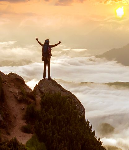 Personal power - person standing triumphantly on a mountain peak